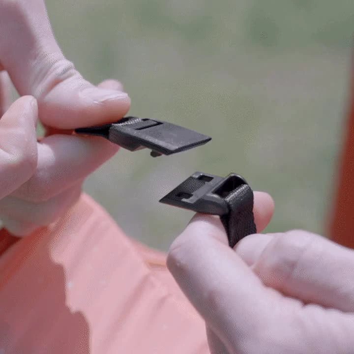 Hands holding the two open magnetic cape clip halves on an orange Kukün blanket.