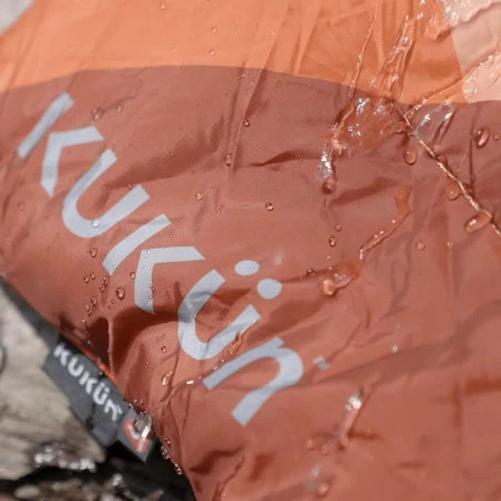 Water beads and runoff on the orange outer fabric of a Kukün blanket.